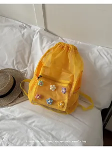 Detailed view of yellow mesh drawstring backpack with handmade crochet flower details.