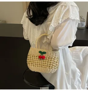 Detailed shot of a pastoral style straw woven handbag with cute cherry and pearl chain.