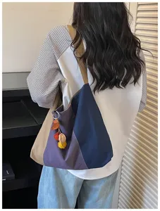 Gedetailleerd overzicht van gekleurde canvas schoudertas gedragen met een schattige hanger.
