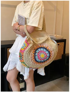 Λεπτομερής κοντινή όψη μιας κομψής boho στρογγυλής ψάθινης τσάντας ώμου με πολύχρωμο μοτίβο.