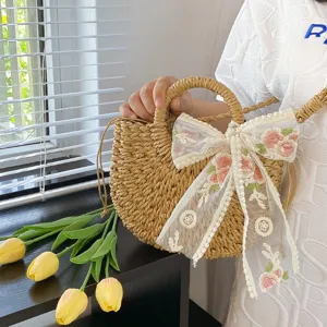 Detalle de bolso de hombro de paja tejida con elegante lazo floral de encaje para la playa.