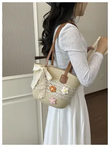 Vue détaillée d'un sac d'épaule en paille tissée avec nœud en dentelle et fleurs.