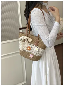 Vue detaillee du sac a epaule en paille avec decor floral et elegant noeud en dentelle.