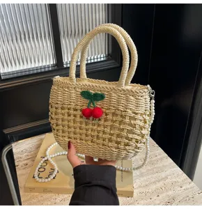 Detailed view of pastoral style woven straw handbag with cute crochet cherry and pearl strap.