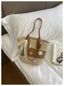 Vue détaillée du sac cabas en paille tissée avec nœud en dentelle et poignées en cuir.