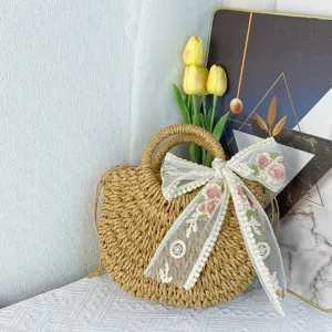 Bolso de mano de paja trenzada con bordado de lazo de encaje, detalle de bolso cruzado de playa.