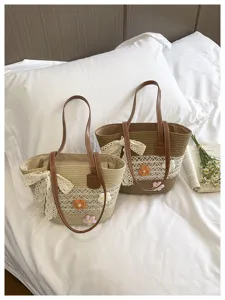 Sac cabas de plage en paille tressée avec nœud en dentelle et fleurs crochetées pour l'été.