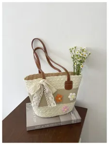 Gros plan sur le sac cabas en paille tressée avec fleurs crochetées et nœud en dentelle.