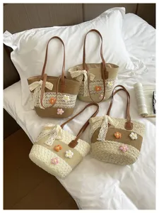 Vue détaillée de sacs à épaule en paille tressée avec fleurs au crochet et nœud en dentelle.