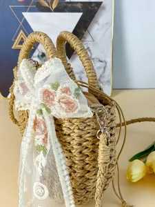 Bolso de mano de paja estilo campestre con lazo de encaje y correa cruzada para la playa.