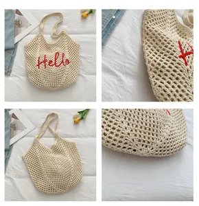 Nahaufnahme Details der beigen gehäkelten Schultertasche mit roter Stickerei für den Strand.