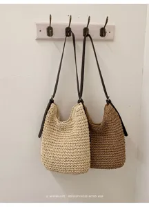 Sac à épaule minimaliste en paille tissée avec lanières en cuir foncé et style rétro chic.