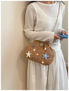 Dettaglio borsa di paglia da spiaggia decorata con stelle marine e conchiglie estive.