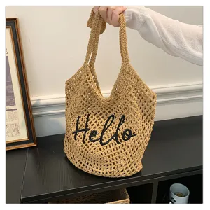 Detailansicht der gehäkelten Strandtasche mit stilvollem schwarzen Hello-Stickmuster.
