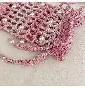 Detailopname van roze gehaakte telefoontas met fijne textuur en prachtige decoratieve parels.