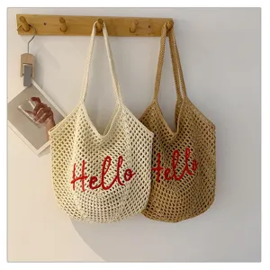Schicke Strandtasche und Umhängetasche aus Baumwolle mit gehäkeltem Lochmuster und roter Bestickung.