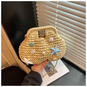 Dettaglio della borsa di paglia da spiaggia con decorazioni di stelle marine e conchiglie.