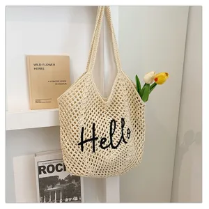 Nahaufnahme der beige gehäkelten gewebten Schultertasche mit schwarzem gesticktem Hello.