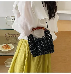 Vista detallada del elegante bolso de mano con cuentas negras y exclusivas asas ambarinas.