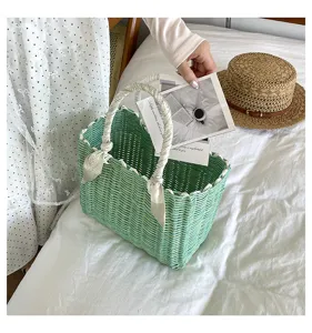 Green woven handbag detail showing textured basket weave and decorative handle scarf.