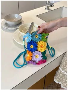 Detailaufnahme der bunten Häkelblumen Handytasche mit handgefertigter Struktur und Riemen.