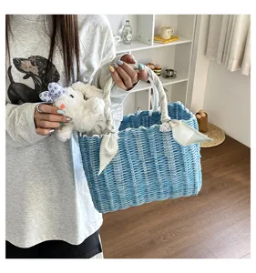 Detail shot of blue woven handbag with cute rabbit plush toy and elegant scarf on handle.