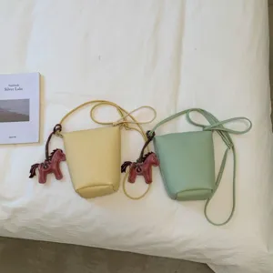 Detailed view of trendy bucket crossbody bags in yellow and green with cute horse charms.