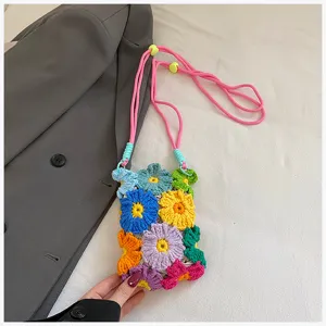 Detailansicht der farbenfrohen handgehäkelten Blumen-Handytasche mit bunten Wollblüten und Riemen.