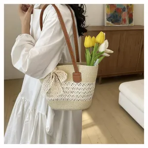 Stylish straw shoulder bag for women, summer beach vacation tote with bow and hollow design.