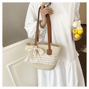 Stylish women straw woven tote bag with brown leather straps and lace bow for beach vacation.