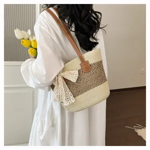 Detail shot of women's woven straw shoulder bag featuring lace bow and leather straps.