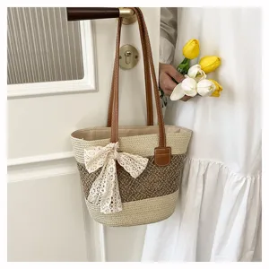 Detailed view of the stylish woven straw handbag featuring elegant lace bow and leather handles.