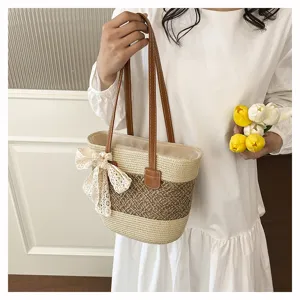 Detail view of the elegant straw woven tote bag featuring chic lace bow and brown straps.