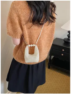 Detailed view of a trendy handmade pearl beaded mini crossbody bag worn on shoulder.