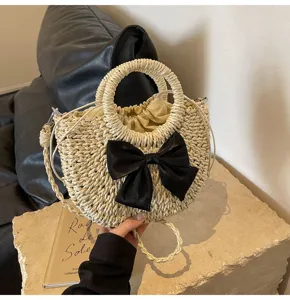 Bolso de mano de paja tejida con lazo negro, ideal para el verano, playa y estilo casual.