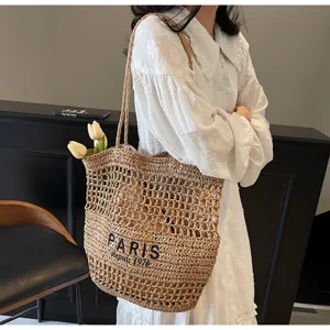Gros plan détaillé du sac cabas d'épaule en paille tissée avec broderie élégante.