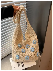 Detalle en primer plano del bolso de hombro de punto crema con flores azules.