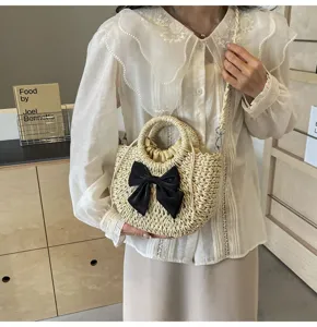 Primer plano de un dulce bolso de paja de estilo campestre con lazo negro para playa.