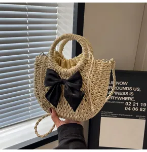Primer plano de bolso bandolera de paja con lazo negro elegante para la playa de verano.