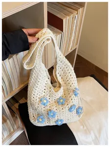 Primer plano detallado del bolso de hombro blanco de ganchillo con bonitas flores azules.