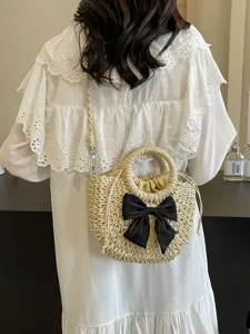 Bolso de paja tejido dulce con lazo negro, perfecto para playa de verano y uso diario elegante.