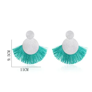 Fan-shaped tassel earrings featuring silver tone discs and turquoise fringe for bohemian style.