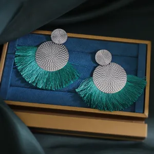 Detailed view of bohemian style green fringe tassel earrings with textured silver discs for women.