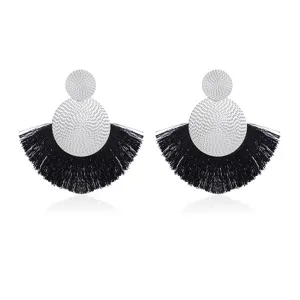 Close-up detail of silver textured disc and black fan tassel earrings bohemian style.