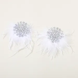 Detailopname van luxe witte veren strass oorbellen met sprankelende kristalclusters.