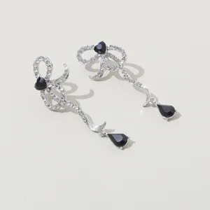 Elegantes pendientes largos de lazo asimétrico con brillantes pedrería y cristales negros.