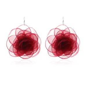 Close-up of red sheer mesh rose earrings, intricate layered floral design, lightweight details.