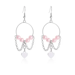 Close-up details van geometrische roze parel oorbellen met hangende kettingen en hanger.