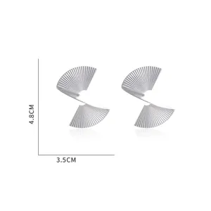 Gros plan de boucles d'oreilles en métal irrégulier en forme d'éventail avec texture spirale.