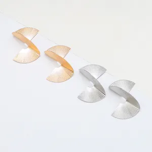 Gros plan de boucles d'oreilles géométriques en métal irrégulier doré et argenté chic.